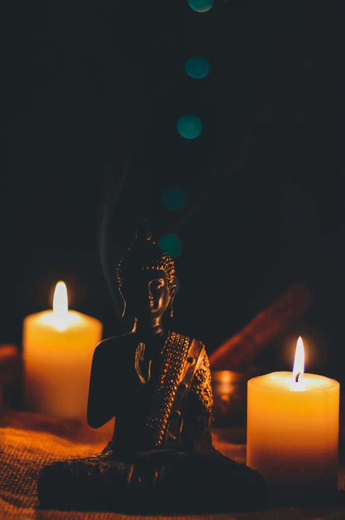 Buddha with two candles symbolising peace and healing