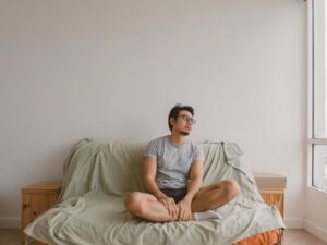 Man sitting cross-legged on bed practising grounding during sexual performance anxiety